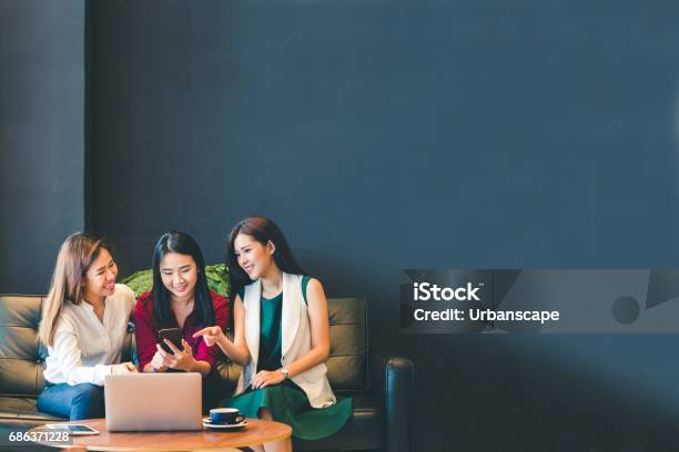 Three Beautiful Asian Girls Using Smartphone And Laptop Chatting On Sofa At Cafe With Copy Space Modern Lifestyle With Gadget Technology Or Working Woman On Casual Business Concept Stock Photo - Download Image Now