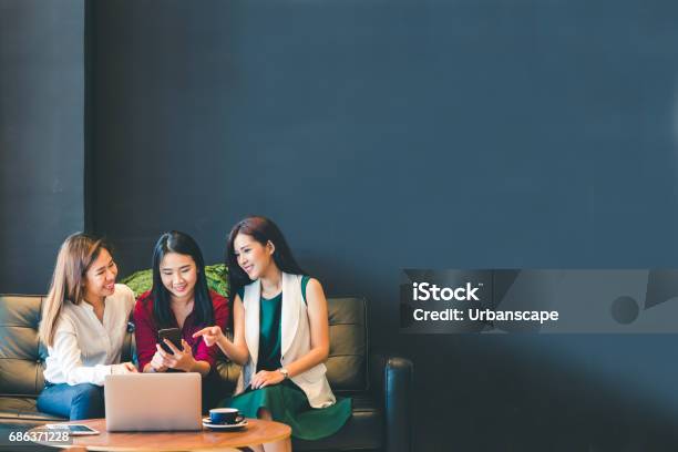 Foto de Três Lindas Garotas Asiáticas Usando Smartphone E Laptop Conversando Sobre O Sofá No Café Com Espaço De Cópia Estilo De Vida Moderno Com Tecnologia Gadget Ou Mulher Trabalhadora No Conceito De Negócios Casuais e mais fotos de stock de Amizade