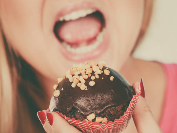Young woman is eating chocolate muffin