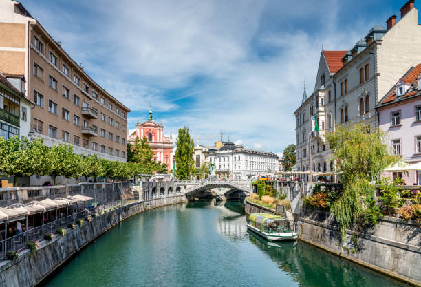 Ljubljana in Summer Ljubljanica River Slovenia Beautiful crowded downtown Ljubljana City with Bars and Restaurants along the Ljubljanica River. View to the famous Tromostovje - Triple Bridge in Summer.  Ljubljana, Slovenia slovenia stock pictures, royalty-free photos & images