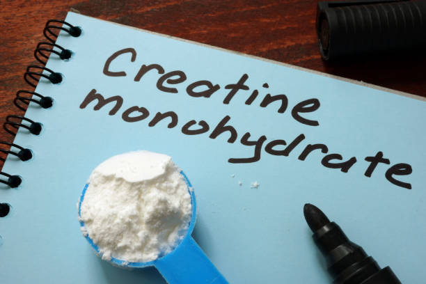 Notebook with  sign Creatine monohydrate and scoop with white powder.