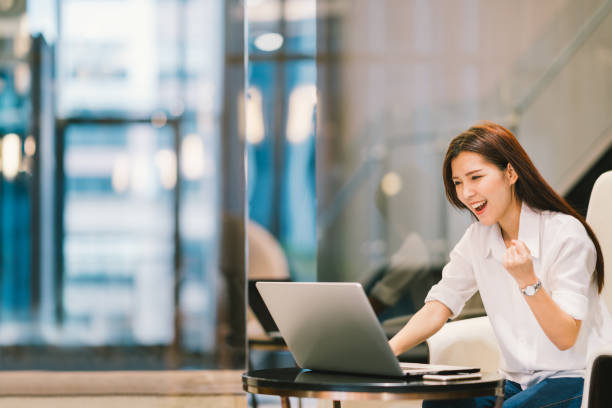 bella ragazza asiatica festeggiare con laptop, successo o posa felice, istruzione o tecnologia o concetto di startup business, ufficio moderno o soggiorno con spazio di copia - japanese ethnicity college student student asian ethnicity foto e immagini stock