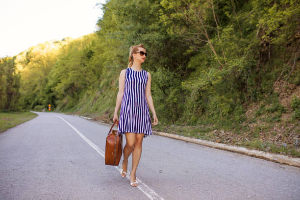 Traveler woman walking with suitcase on road