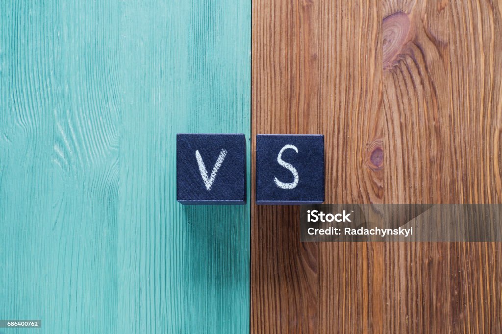 Letters VS on wooden background with copy space. Letters VS on wooden background with copy space. The concept of making choice.  Versus letters. Turquoise and brown wooden background and black cubes with letters VS. Confrontation Stock Photo