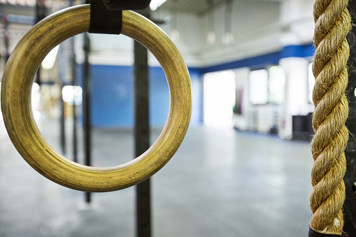 Close-up of gymnastic ring by rope in gym. Exercise equipment is in health club.