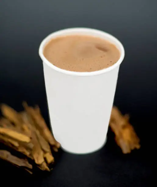 A cup of chocolate and cinnamon on a black background
