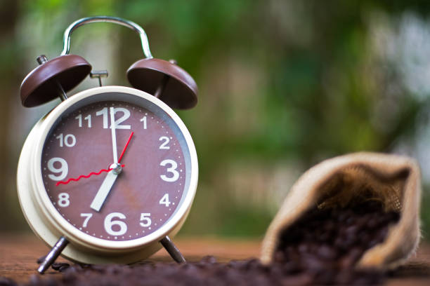 istock Alarm clock with coffee beans on wooden table with morning light, Start up concept, select focus clock 686438828