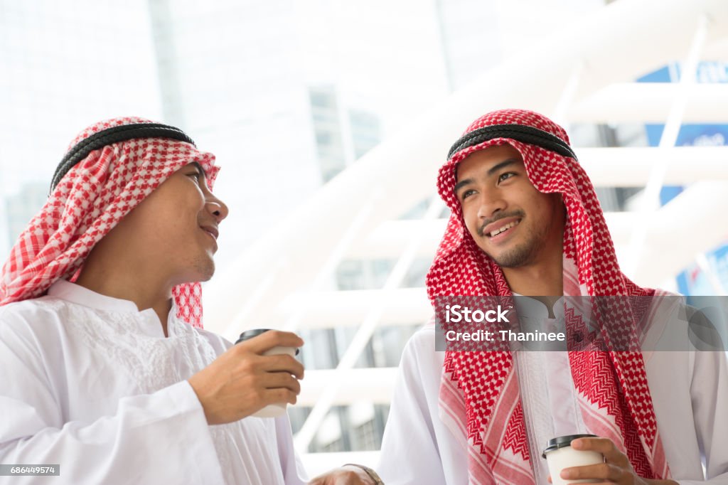 Two Arabian businessman are celebrating their project together is the city Two young Arabian business man are standing in the city. Successful concept Adult Stock Photo