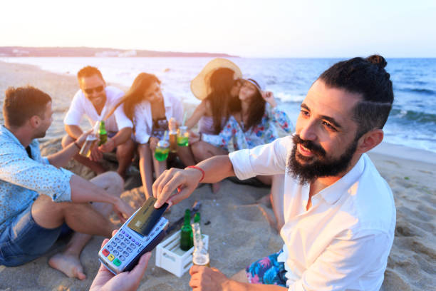 istock Young man using credit card for contactless payment on beach 686488356