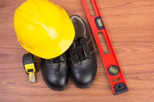 Top view safety shoes and composition of working tools on wooden table