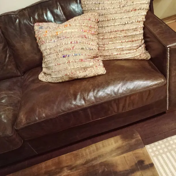 Classic brown leather sofa with two decorative cushions.