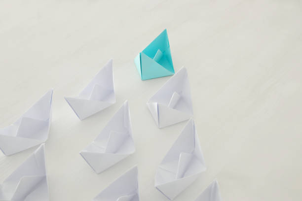 istock leadership concept, blue paper boat leading followers 686509158