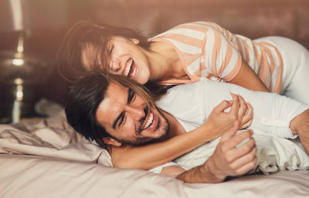 heureux jeune couple au lit - flirter photos et images de collection