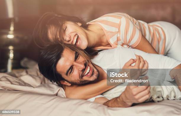 Happy Young Couple In Bed Stock Photo - Download Image Now - Couple - Relationship, Bed - Furniture, Happiness