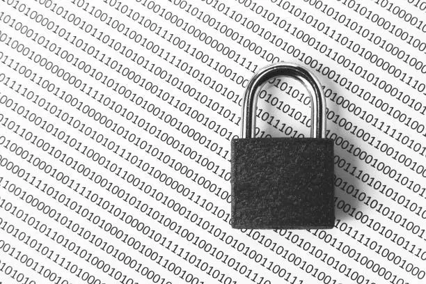 Photo of a black and white concept image that can be used to represent cyber security or the protection of software code. This image has selective focusing on the padlock