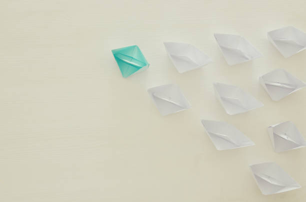 istock paper boats and one individual boat choosing different path 686528730