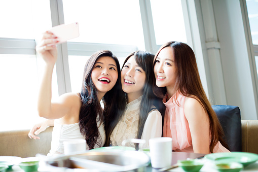 happy young girl friend taking selfie together in restaurant