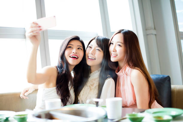 happy young girl friend taking selfie together in restaurant happy young girl friend taking selfie together in restaurant japanese girlfriends stock pictures, royalty-free photos & images