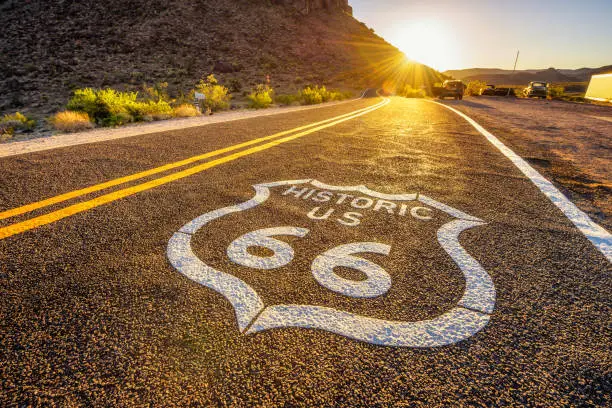 Street sign on historic route 66 in the Mojave desert photographed against the sun at sunset