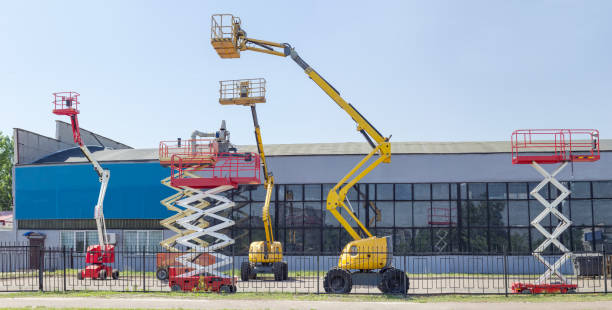 Several different scissor and articulated boom wheeled lifts Several different wheeled scissor lifts and wheeled articulated lifts with telescoping boom and basket on an asphalt ground against the sky and an industrial building mobile crane stock pictures, royalty-free photos & images