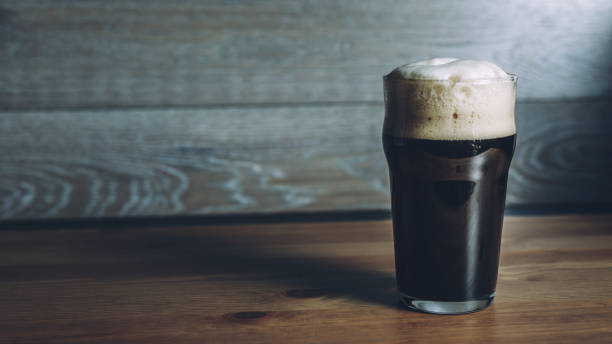 Glass of dark beer on wooden surface stock photo