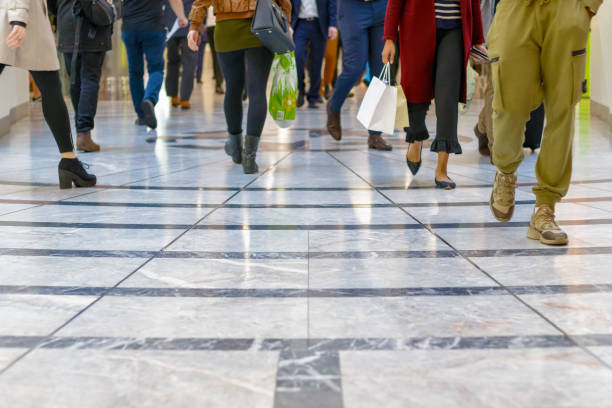 un piso moderno con patas de una muchedumbre caminando en el fondo - retail people customer shopping fotografías e imágenes de stock