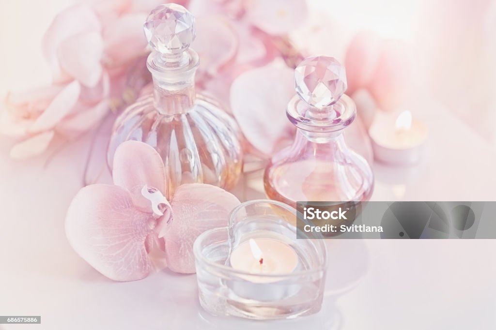 botellas de aceites de perfume y aromático rodeadas de flores y cand - Foto de stock de Aceites esenciales libre de derechos