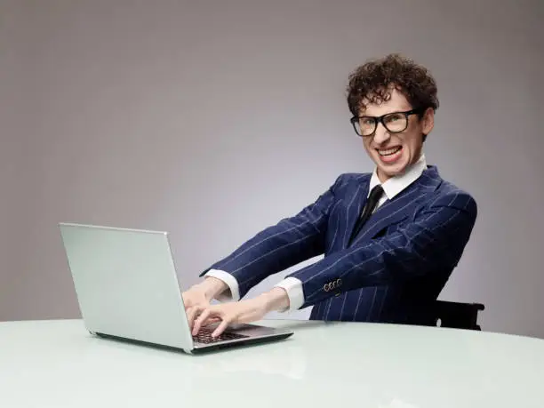 Funny business man geek using laptop with evil genius facial expression