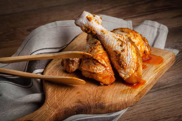 istock Marinated chicken drumsticks on a wooden chopping board. 686588264