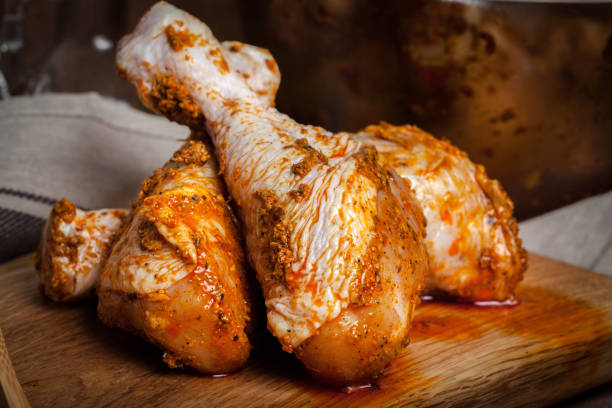 istock Marinated chicken drumsticks on a wooden chopping board. 686588328