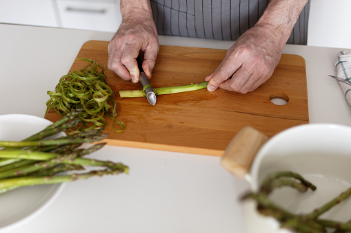 Man peeling asparagus on a rustic cutting board