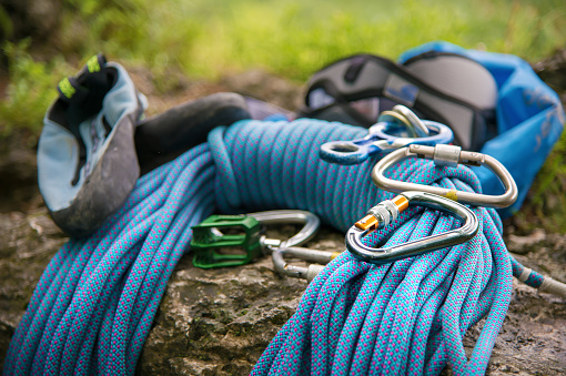 Close up Used equipment for climbing where the rope carbines and climbing slippers lie on a rock