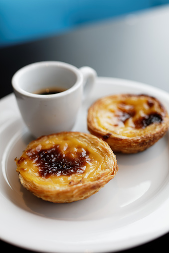 Portuguese egg tart pastry Pastel de nata on a plate with a cup of black coffee