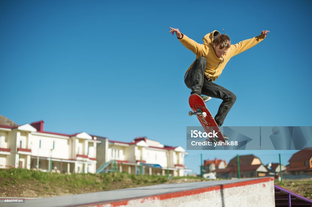 Un skater adolescente hace un truco de ollie en un skatepark en las afueras de la ciudad - Foto de stock de Monopatín - Actividades recreativas libre de derechos