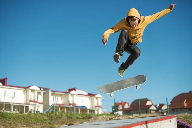 A teenager skateboarder does an flip trick in a skatepark on the outskirts of the city stock photo