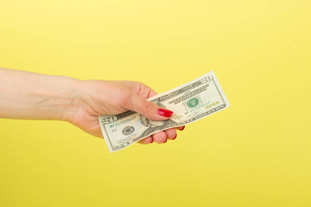 istock Twenty dollars in the woman's hand, yellow background 686604278