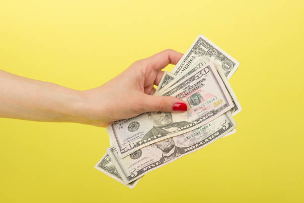 istock Fifty, five and one dollars in the woman's hand, yellow background 686606576