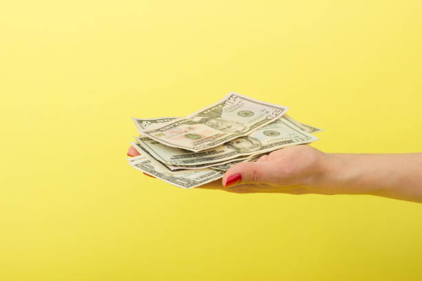 istock Fifty, twenty, five and one dollars in the woman's hand, yellow background 686606696