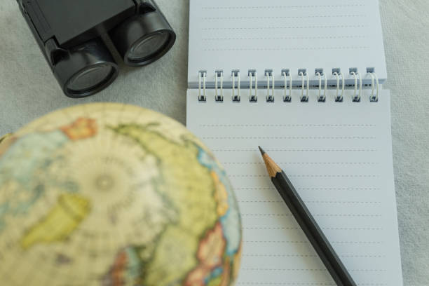 istock World travel concept with pencil on white note paper, binoculars and small globe on white background 686619292