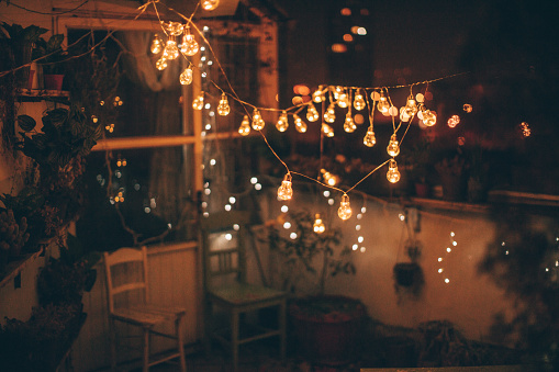 Photo of a charming little balcony over the city, decorated with lightning bulbs