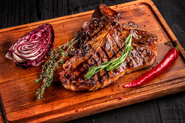 istock Medium rare grilled steak on rustic cutting board with rosemary and spices , dark rustic wooden background, top view 686623176