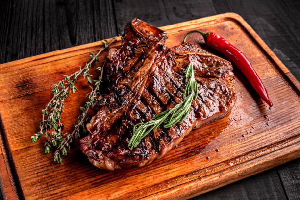 istock Medium rare grilled steak on rustic cutting board with rosemary and spices , dark rustic wooden background, top view 686623218