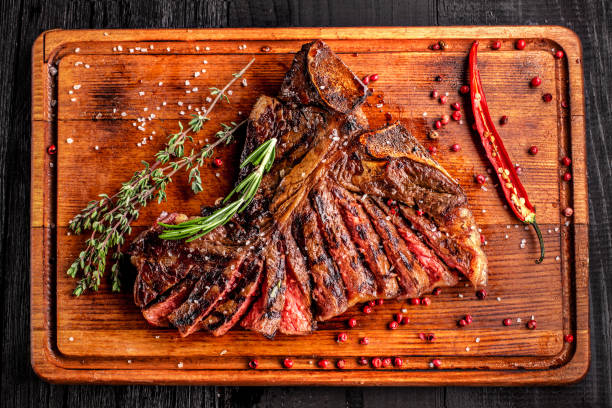 istock Sliced medium rare grilled steak on rustic cutting board with rosemary and spices , dark rustic wooden background, top view 686623290