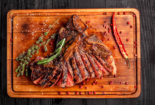 istock Sliced medium rare grilled steak on rustic cutting board with rosemary and spices , dark rustic wooden background, top view 686623344
