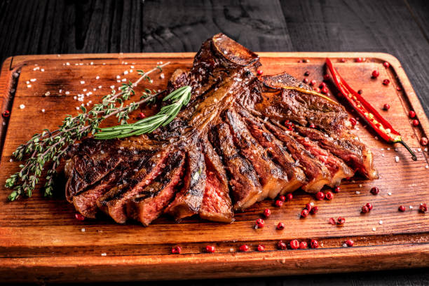 istock Sliced medium rare grilled steak on rustic cutting board with rosemary and spices , dark rustic wooden background, top view 686623400