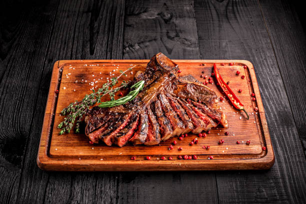 istock Sliced medium rare grilled steak on rustic cutting board with rosemary and spices , dark rustic wooden background, top view 686623470