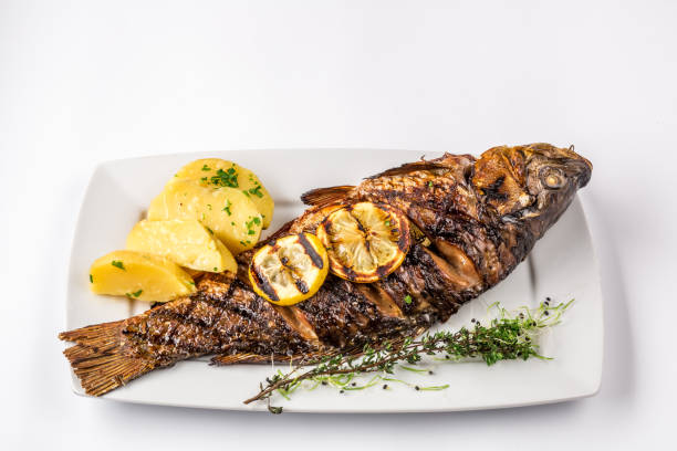 Grilled carp fish with rosemary potatoes and lemon, close up stock photo