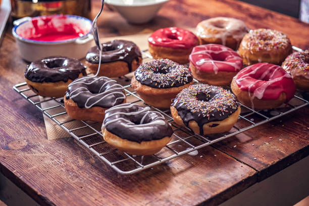 Preparing Homemade Donuts Preparing various homemade donuts with colored icing and chocolate. donuts stock pictures, royalty-free photos & images