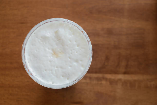 istock Milk froth in a cup on wood table, top view 686627942