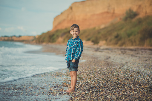 Portrait of happy boy standing alone at beach.